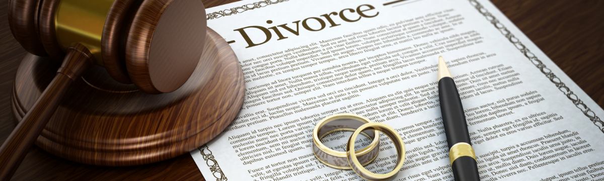 a document that says divorce, laying flat on a table with wedding rings sitting on top.